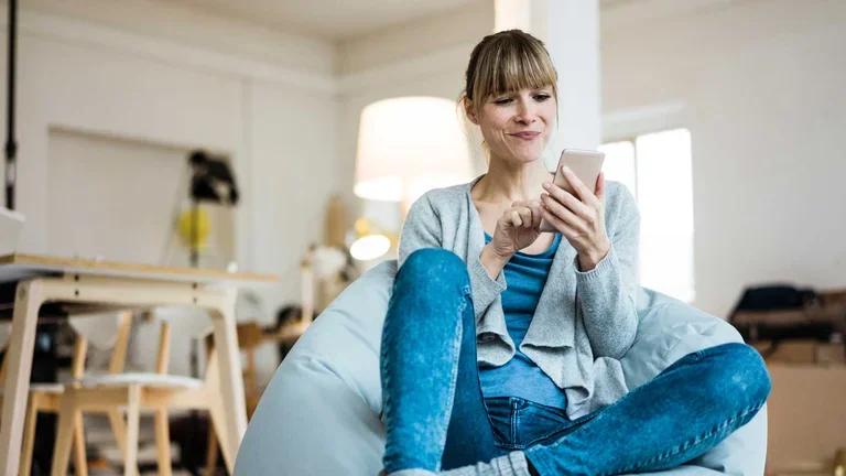 Frau sitzt mit einem Smartphone in der Hand auf einem Sitzsack