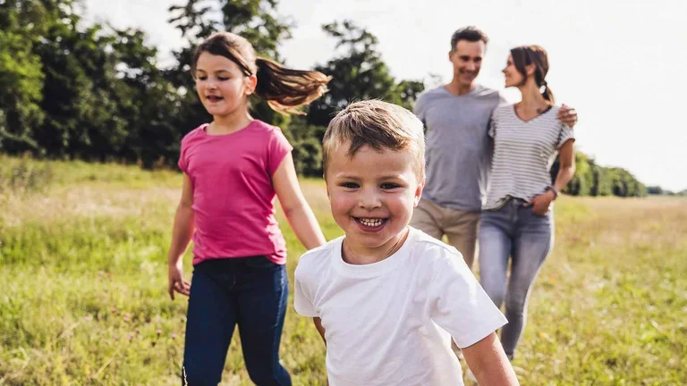 Kleiner Patient der Chelat-Therapie bei Eisenüberladung mit seiner Familie läuft auf einem Feld