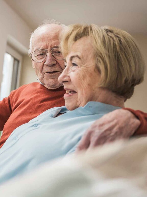 Patientin Schmerztherapie (PCA) mit ihrem Mann auf den Sofa im Gespräch