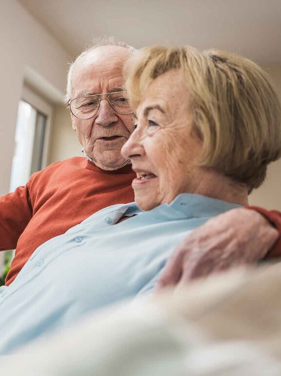 Patientin Schmerztherapie (PCA) mit ihrem Mann auf den Sofa im Gespräch